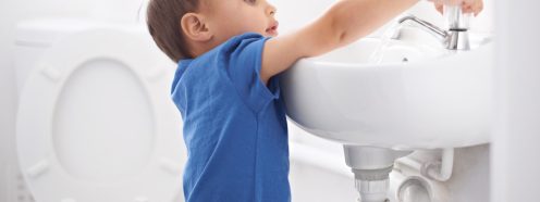 Shot of a cute young boy washing his hands in a bathroom