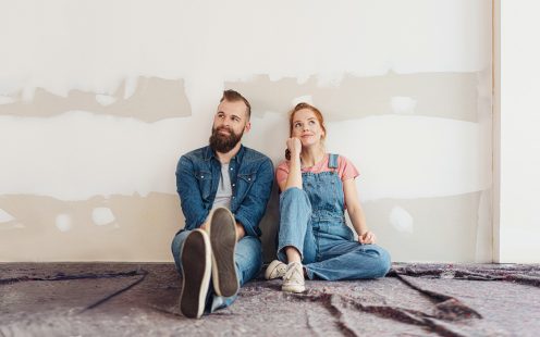 Two young people sitting on the floor in a room undergoing renovation.