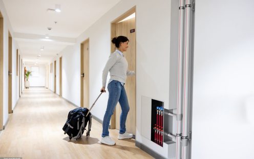 Latin American traveler opening the door and entering her room at a hotel - travel concepts