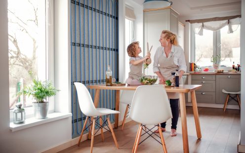 A 3D visualisation revealing a wall heating system installed in a kitchen where a mother and a child are cooking together.