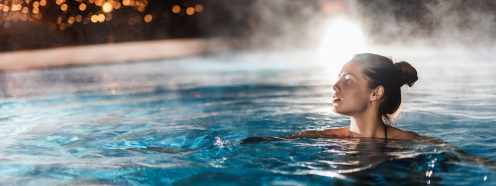 Beautiful woman swimming in a swimming pool with steam.